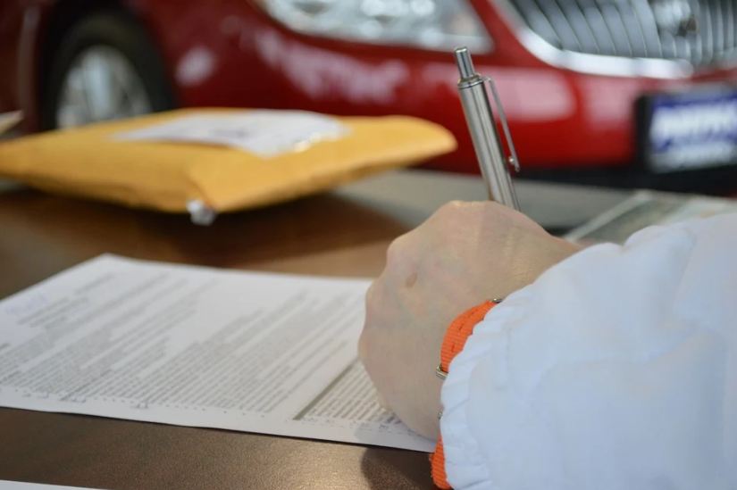 signing a contract, yellow folder, red car at the back