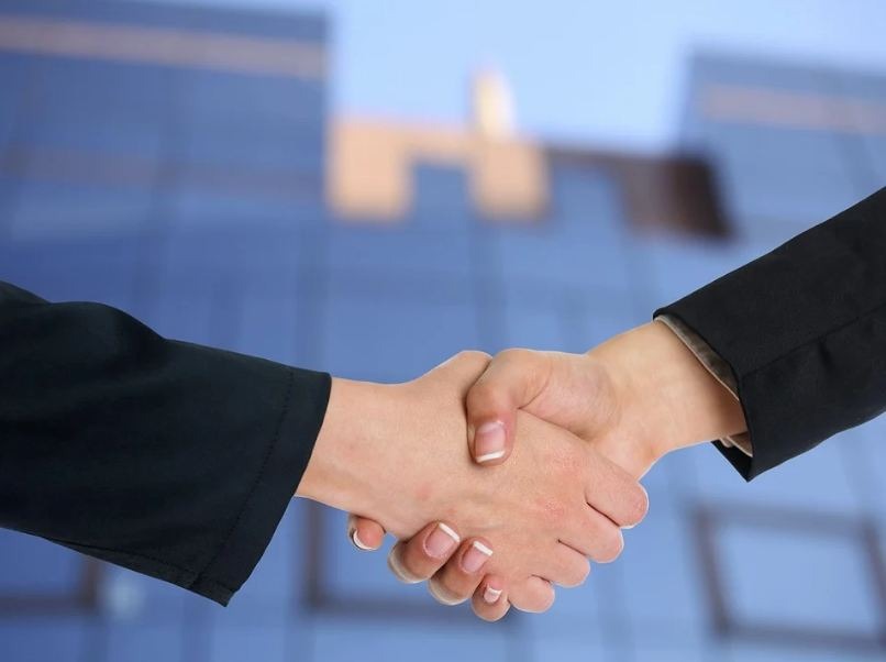two people shaking hands, black long sleeves, blue background