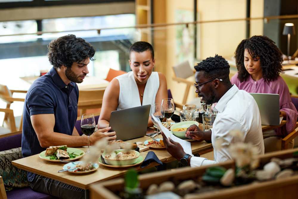 A multicultural busy businesspeople are working on a start-up project in a restaurant at the dinner table