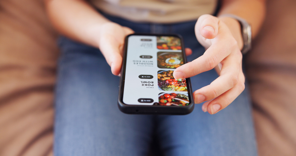 Hands, phone and person in home on app for online order of food for dinner, lunch or supper. Technology, browsing and customer scrolling on restaurant website for meal with delivery at apartment