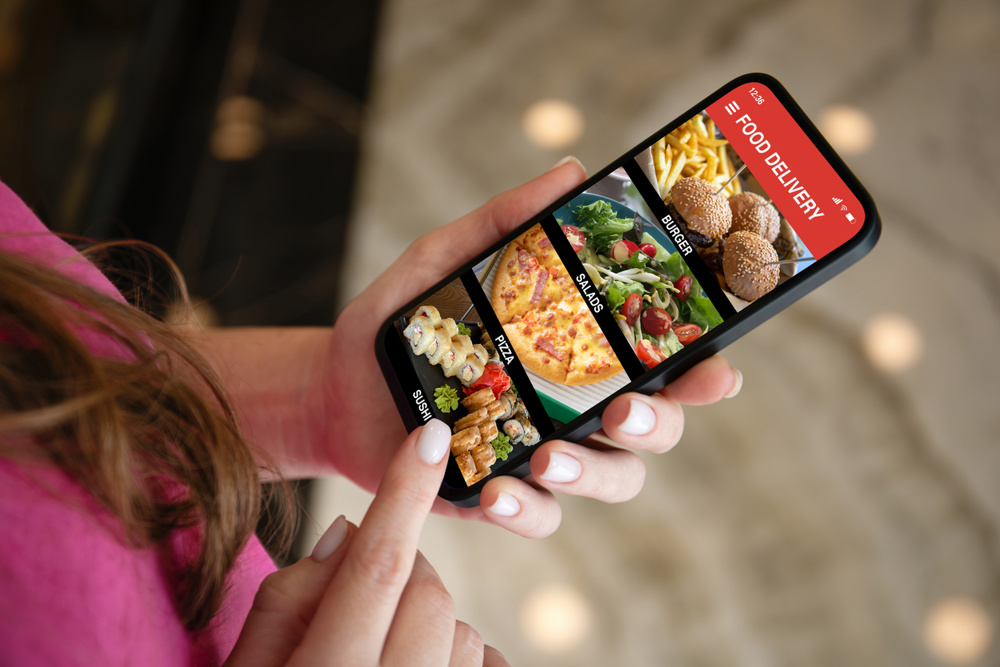 Woman hands holding phone with food delivery app on screen background of street lights