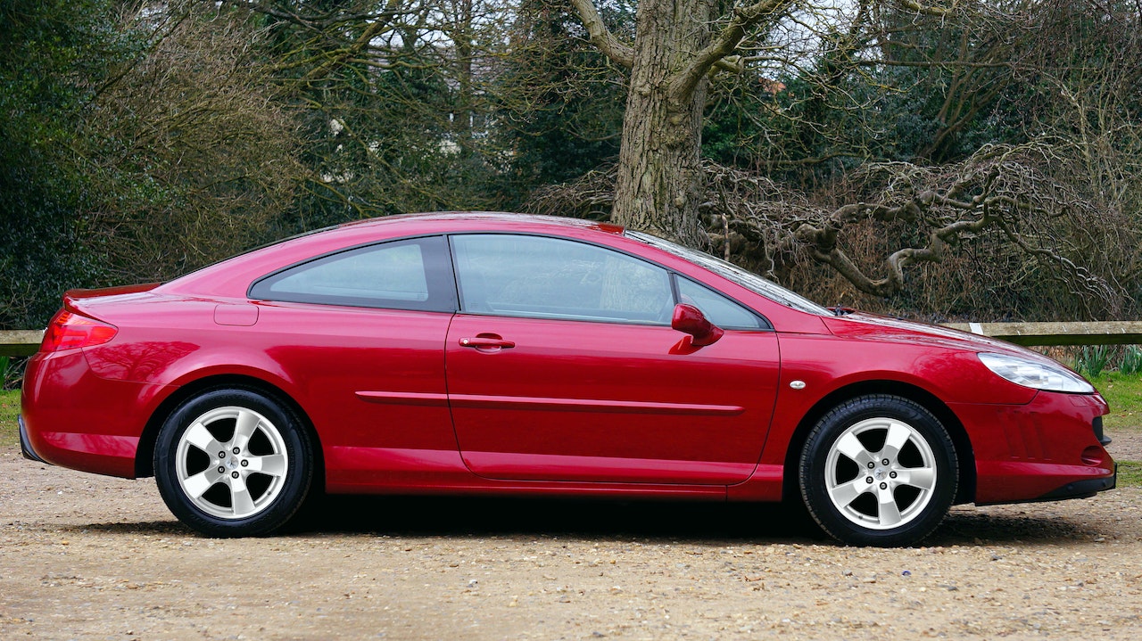 Red Coupe parked near a tree